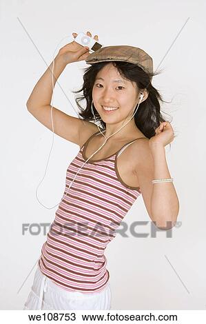 Asian teen listening to music on an MP3 playing on a white background View Large Photo Image Stock Image - Asian teen listening to music on an MP3 playing on a white background. Fotosearch