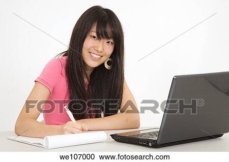 Stock Image - Asian teenager working on a the laptop computer on white background. Fotosearch