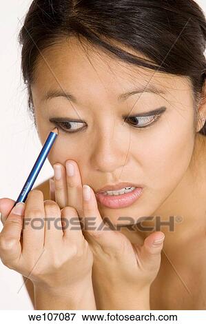 Asian woman applying eye make up View Large Photo Image Stock Photo - Asian woman applying eye make up. Fotosearch