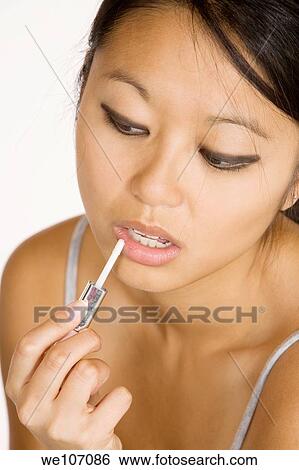 Asian woman applying lipgloss View Large Photo Image Stock Photograph - Asian woman applying lipgloss. Fotosearch