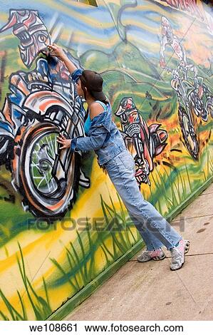 Beautiful Brazilian girl spray painting a mural on the side of a building View Large Photo Image Stock Image - Beautiful Brazilian girl spray painting a mural on the side of a building. Fotosearch