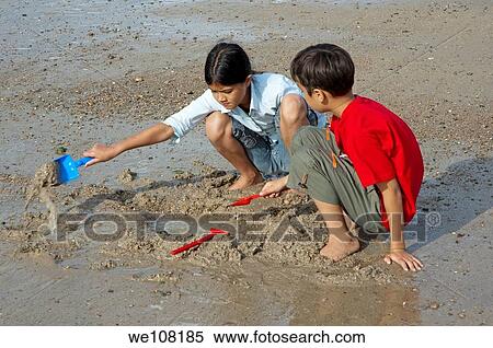 Stock Photography - Brother and sister playing in the sand with spades, Anse du Guesclin, Brittany, France. Fotosearch