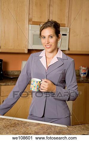 Businesswoman in early 20s standing in the kitchen dresses in a business suit and holding a coffee cup View Large Photo Image Stock Image - Businesswoman in early 20s standing in the kitchen dresses in a business suit and holding a coffee cup. Fotosearch
