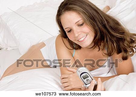 Caucasian woman in early 20's laying in bed talking on cell phone View Large Photo Image Stock Image - Caucasian woman in early 20's laying in bed talking on cell phone. Fotosearch
