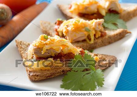 Stock Image - Dietetic wheat toasts with tuna, tomato sauce, grated carrots and a leaf of coriander. Fotosearch