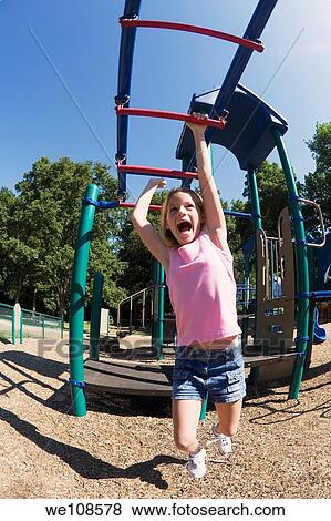 Eleven year old girl playing on gym bars in park View Large Photo Image Stock Photo - Eleven year old girl playing on gym bars in park. Fotosearch