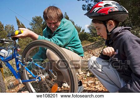 Father helping his son repair the flat tyre of his mountain bike View Large Photo Image Stock Image - Father helping his son repair the flat tyre of his mountain bike. Fotosearch