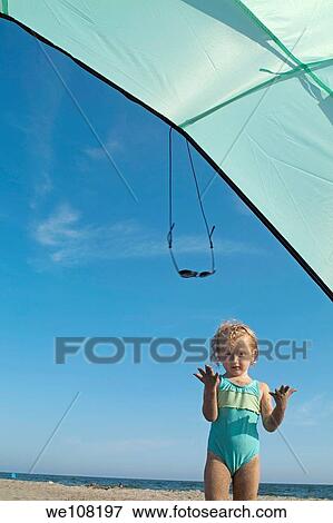 Little girl playing under a sunshade at the beach, Camargue, France View Large Photo Image Stock Photo - Little girl playing under a sunshade at the beach, Camargue, France. Fotosearch