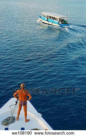 Man standing on a ship's bow looking out to sea at a Dhoni boat, Maldives View Large Photo Image Stock Image - Man standing on a ship's bow looking out to sea at a Dhoni boat, Maldives. Fotosearch