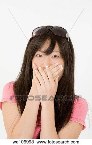 Portrait of a beautiful Asian teenager posing on a white background with hands over mouth View Large Photo Image Stock Photo - Portrait of a beautiful Asian teenager posing on a white background with hands over mouth. Fotosearch