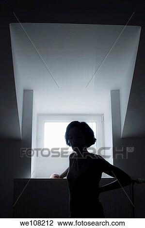 Silhouette of a lonely woman standing in front of a window View Large Photo Image Stock Image - Silhouette of a lonely woman standing in front of a window. Fotosearch