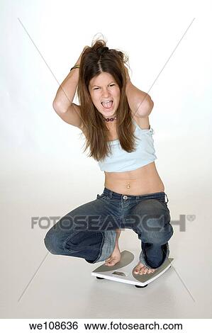 Teenage girl weighting herself and up set because her feels she is gaining weight View Large Photo Image Stock Photograph - Teenage girl weighting herself and up set because her feels she is gaining weight. Fotosearch