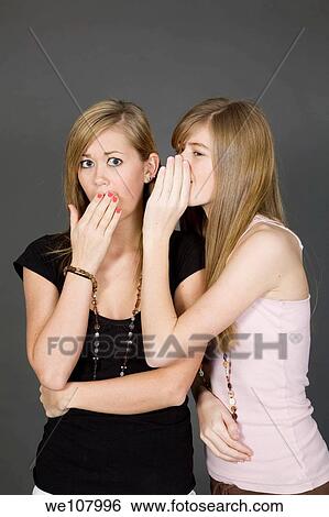 Teenage girls telling secrets posed in front of a gray background View Large Photo Image Stock Photograph - Teenage girls telling secrets posed in front of a gray background. Fotosearch