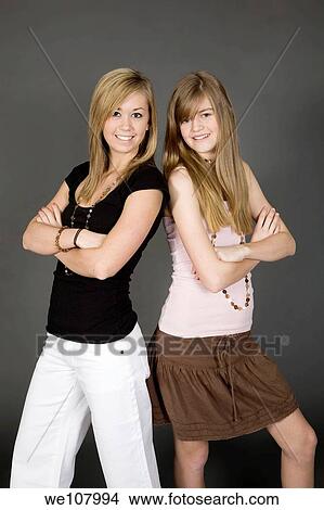 Teenage sisters posed in front of a gray background View Large Photo Image Picture - Teenage sisters posed in front of a gray background. Fotosearch