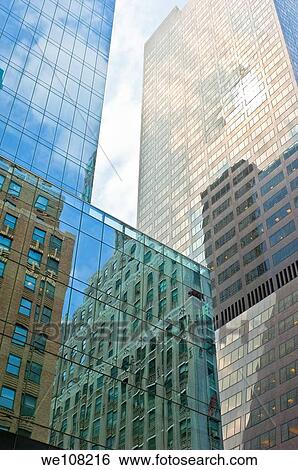 View upwards of tall modern buildings in New York City with blue sky and white clouds. View Large Photo Image Stock Photograph - View upwards of tall modern buildings in New York City with blue sky and white clouds.. Fotosearch