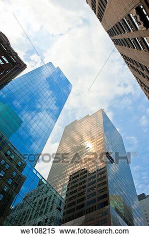 View upwards of tall modern buildings in New York City with blue sky and white clouds. View Large Photo Image Stock Photography - View upwards of tall modern buildings in New York City with blue sky and white clouds.. Fotosearch