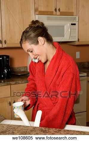 Woman in early 20s standing in the kitchen talking on the telephone View Large Photo Image Stock Photography - Woman in early 20s standing in the kitchen talking on the telephone. Fotosearch