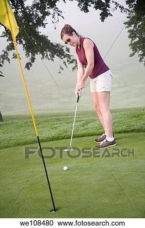 Stock Image - Woman in her mid 20s playing golf. Fotosearch