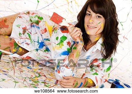 Woman in mid 20s having fun making a mess painting View Large Photo Image Picture - Woman in mid 20s having fun making a mess painting. Fotosearch