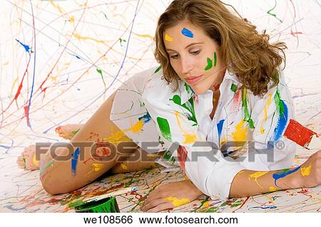 Woman in mid 20s having fun making a mess painting View Large Photo Image Stock Photograph - Woman in mid 20s having fun making a mess painting. Fotosearch
