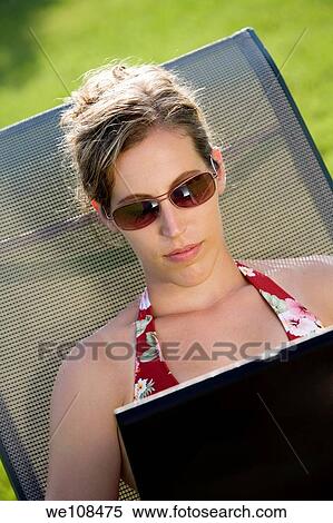 Woman in mid 20s sunbathing and working on a laptop computer View Large Photo Image Stock Photography - Woman in mid 20s sunbathing and working on a laptop computer. Fotosearch