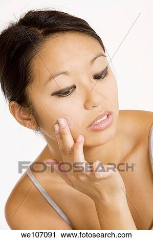 Young Asian woman applying moisturizing cream on her face View Large Photo Image Stock Image - Young Asian woman applying moisturizing cream on her face. Fotosearch