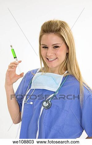 Young caucasian female nurse wearing scrubs outfit and holding a hypodermic syringe View Large Photo Image Stock Image - Young caucasian female nurse wearing scrubs outfit and holding a hypodermic syringe. Fotosearch