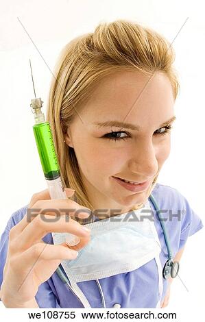 Young caucasian female nurse wearing scrubs outfit and holding a syringe View Large Photo Image Stock Photography - Young caucasian female nurse wearing scrubs outfit and holding a syringe. Fotosearch