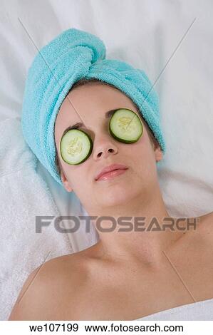 Young woman having a relaxing moment during a message with cucumbers on her eyes View Large Photo Image Stock Photo - Young woman having a relaxing moment during a message with cucumbers on her eyes. Fotosearch