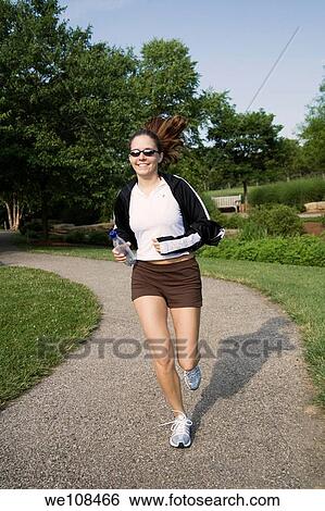 Young woman in early 20s jogging in park View Large Photo Image Stock Photograph - Young woman in early 20s jogging in park. Fotosearch