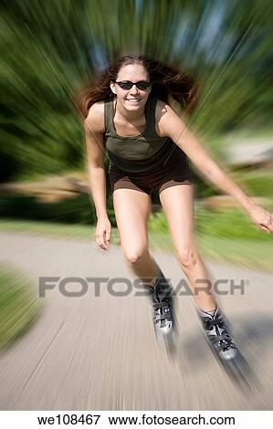 Young woman in early 20s roller blading in park View Large Photo Image Stock Photo - Young woman in early 20s roller blading in park. Fotosearch