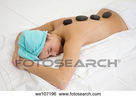 Young woman relaxing during a message using stone therapy View Large Photo Image Stock Photograph - Young woman relaxing during a message using stone therapy. Fotosearch