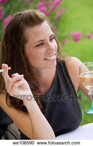 Young woman relaxing with a glass of wine and a cigarette in an outdoor cafe View Large Photo Image Stock Image - Young woman relaxing with a glass of wine and a cigarette in an outdoor cafe. Fotosearch