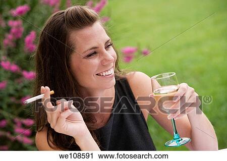 Young woman relaxing with a glass of wine and a cigarette in an outdoor cafe View Large Photo Image Stock Image - Young woman relaxing with a glass of wine and a cigarette in an outdoor cafe. Fotosearch