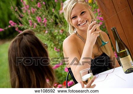 Young women relaxing with a glass of wine in an outdoor cafe View Large Photo Image Stock Image - Young women relaxing with a glass of wine in an outdoor cafe. Fotosearch