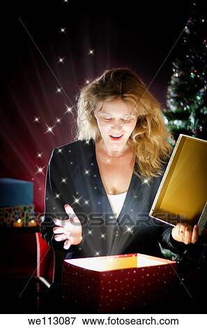 Stock Photo - Blond woman opening Christmas present. Fotosearch