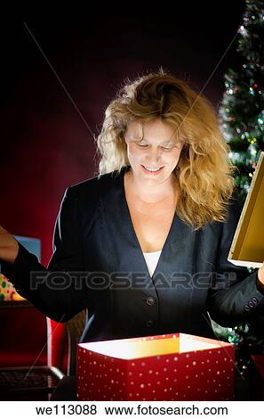 Stock Photo - Blond woman opening Christmas present. Fotosearch