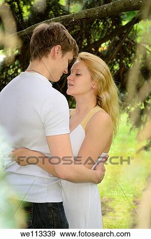 Embracing couple in love hidden in a large spruce tree in a park View Large Photo Image Stock Photo - Embracing couple in love hidden in a large spruce tree in a park. Fotosearch