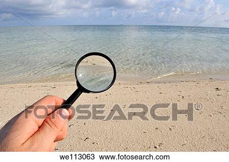 Hand holding a magnifying glass on a tropical beach, sland of Borneo, Sabah State, Malaysia View Large Photo Image Stock Image - Hand holding a magnifying glass on a tropical beach, sland of Borneo, Sabah State, Malaysia. Fotosearch