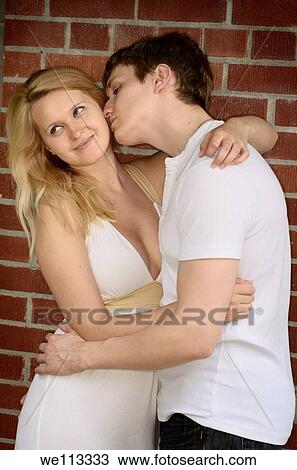 Man moving to kiss a demure woman standing by a brick wall View Large Photo Image Stock Image - Man moving to kiss a demure woman standing by a brick wall. Fotosearch