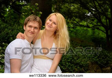 Smiling couple with woman sitting on lovers lap in a forest View Large Photo Image Stock Photograph - Smiling couple with woman sitting on lovers lap in a forest. Fotosearch