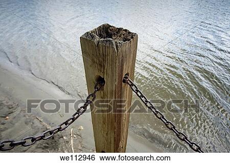 Stock Photograph - Wooden beam and metal chains from a pier. Fotosearch