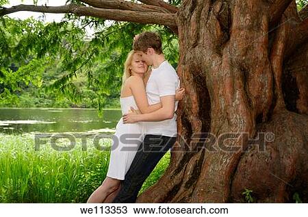 Couple embracing under a large Dawn Redwood tree on the shore of a lake View Large Photo Image Stock Image - Couple embracing under a large Dawn Redwood tree on the shore of a lake. Fotosearch