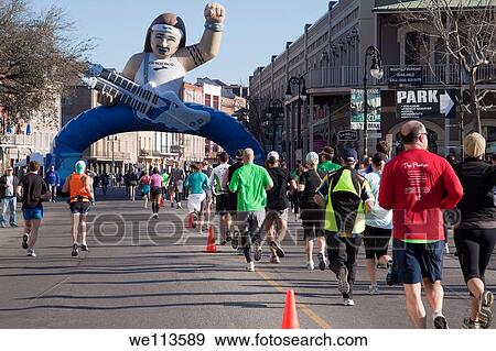 Stock Photo - Crowd of racers running toward the giant inflated guitar player on Decatur Street in the Rock and Roll Marathon in New Orleans. Fotosearch