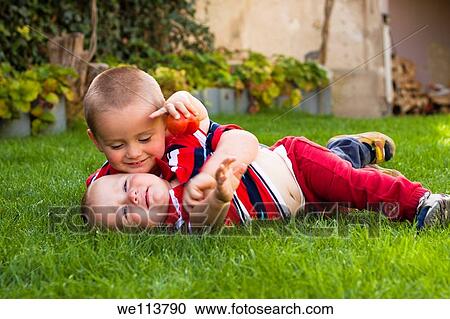 Stock Image - Cute little brothers playing in the grass. Fotosearch