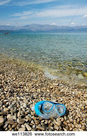Stock Photograph - Diving mask lying on pebble beach, Croatia. Fotosearch