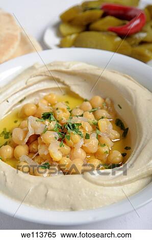 Stock Photography - Hummus A Levantine Arab dip or spread made from cooked, mashed chickpeas, blended with tahini, olive oil, lemon juice, salt and garlic Garnished with cooked chickpeas. Fotosearch