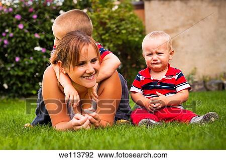 Stock Image - Portrait of beautiful young mother with two kids in the garden. Fotosearch