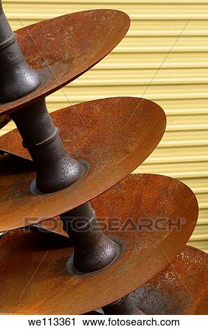 Stock Image - Red rusted metal disks of a farm plough attachment. Fotosearch