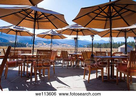 Umbrellas over outdoor patio dining area at a mountain resort lodge with scenic view of mountain range View Large Photo Image Stock Photograph - Umbrellas over outdoor patio dining area at a mountain resort lodge with scenic view of mountain range. Fotosearch